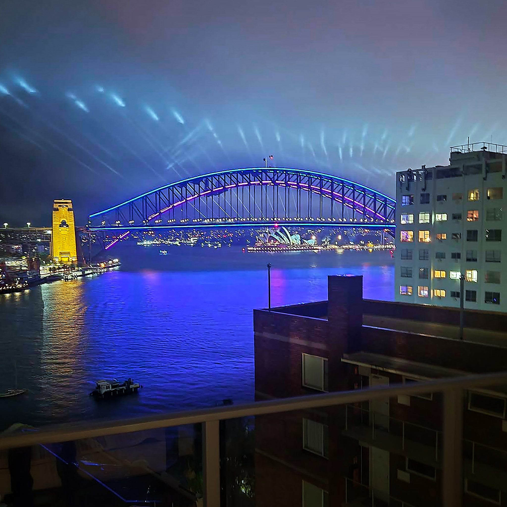 The view of the Sydney Harbour Bridge at night with vivid blue lights creating a glow on the water whilst attending a private certifier industry event in Sydney NSW