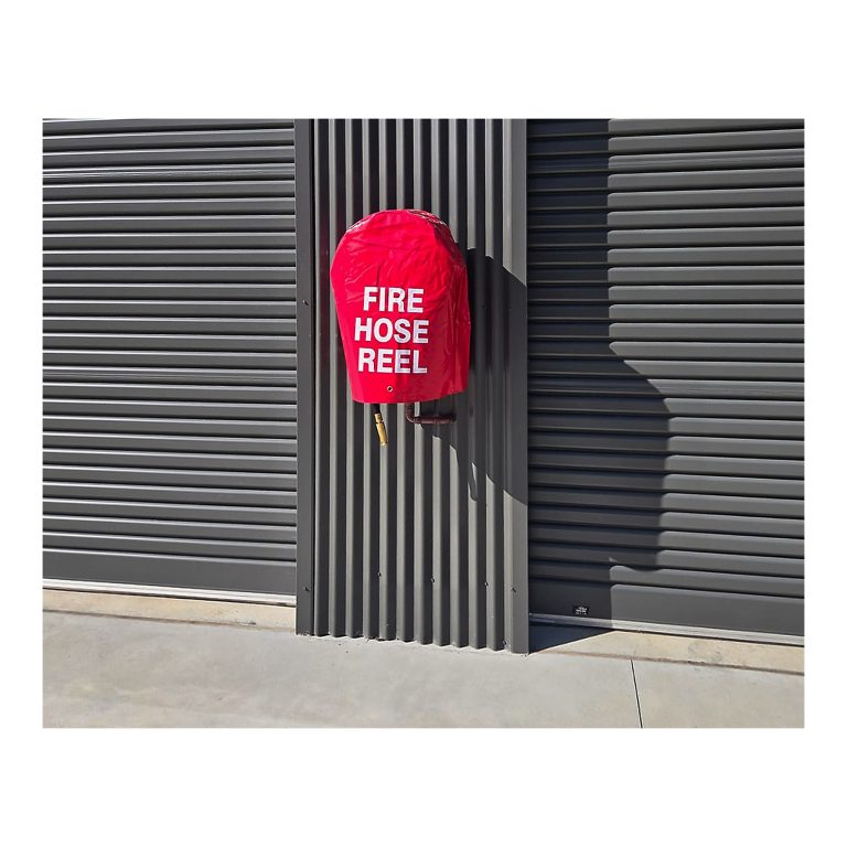 Fire hose reel installed between industrial roller doors, certified commercial premises, Kempsey NSW